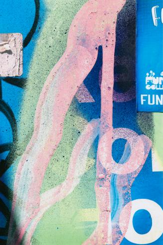 A close-up photograph of a surface covered in posters and graffiti. Portions of posters, some o ...