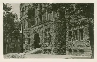 Black and white photograph of a Richardsonian Romanesque building covered in ivy.