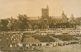Sepia toned photograph of a very large stone building with many towers. Soldiers on parade in f ...