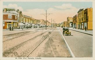 Colorized photograph of a city street with buildings on each side of it, automobile in the midd ...