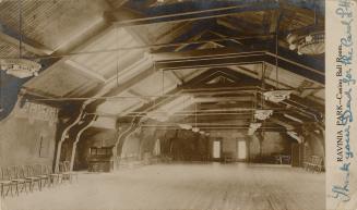 Black and white photograph of an empty ballroom with a vaulted ceiling.