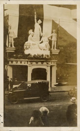 A photograph of a storefront with a number of large statues above an entrance or doorway. The s ...