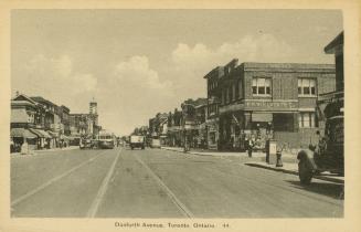 Black and white photograph of a city street with automobiles and streetcars.