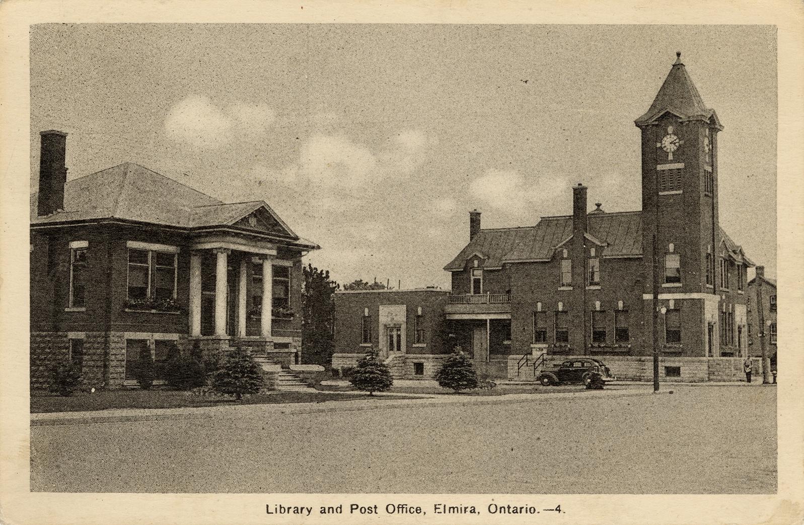 Picture of wide street showing public library building and post office building to the right. 