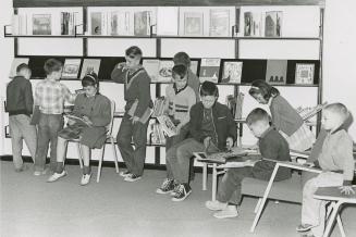 Picture of boys and girls looking at books in a library.
