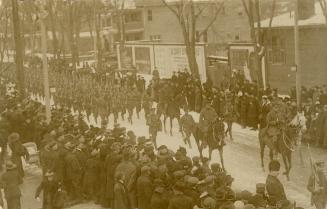 Black and white picture of soldiers marching on an icy city street while crowds of civilians lo ...