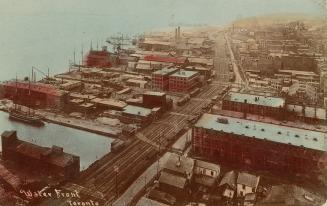 Colour photo postcard depicting an aerial view of buildings and the train track along the water ...