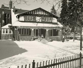 Picture of an arts and craft style house with lawn covered in snow. 
