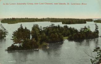 Colorized photograph of a body of water with wilderness surrounding it; forested islands in the ...