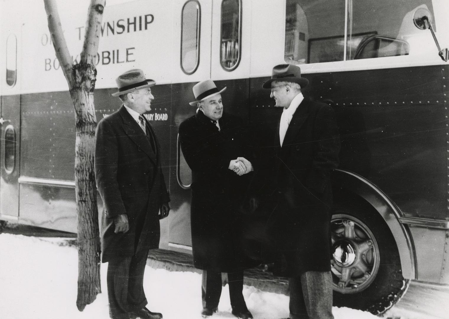 Picture of three men in front of a bookmobile. 