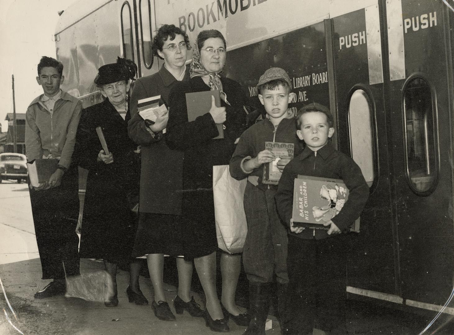 Picture of six women and children lined up at a bookmobile. 