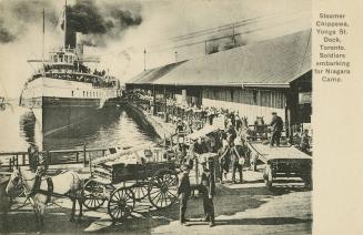 Black and white photo postcard depicting soldiers onboarding a steam ship to embark on their jo ...
