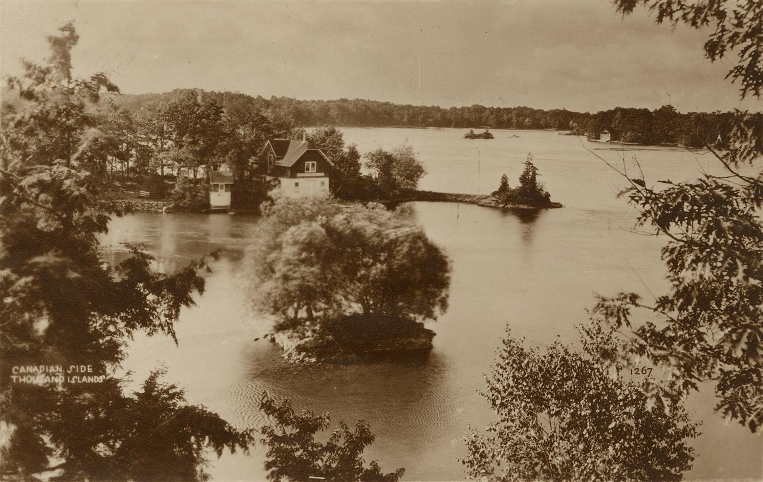 Sepia toned photograph of islands in the middle of a wide river. One Island has a house on it.