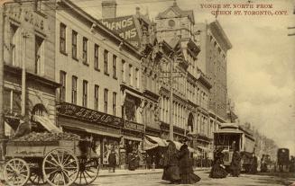 Sepia-toned photo postcard depicting a view of Yonge Street with many shops, a streetcar, and p ...