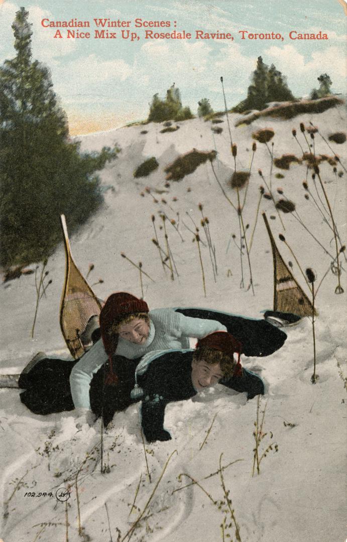 Colorized photograph of a two girls on snow shoes who have fallen down on top of each other.