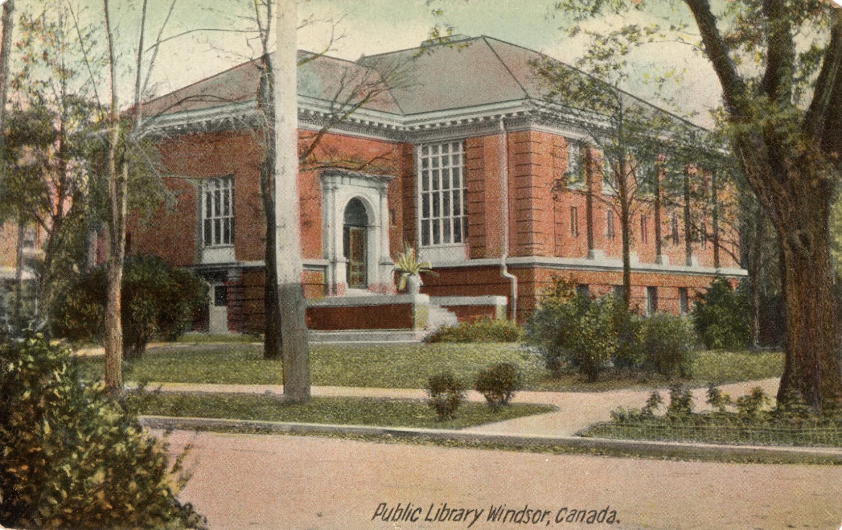 Picture of large brick library building with trees in front. 