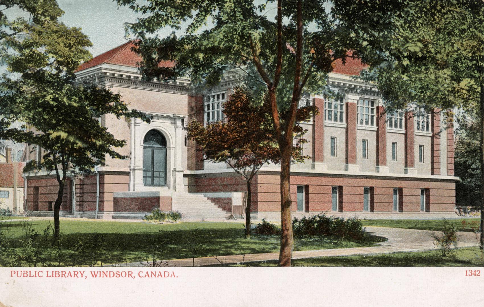 Picture of large brick library building with trees in front. 