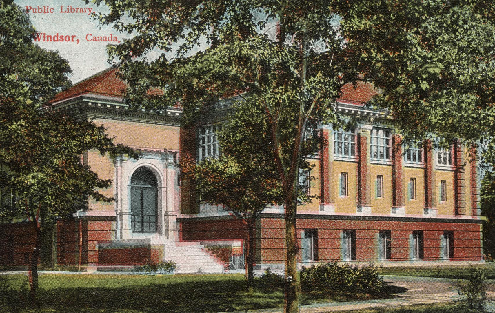 Picture of large brick library building with trees in front. 