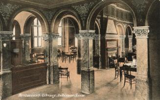 Picture of the interior of a library with arches, fireplace and wooden desk and tables. 