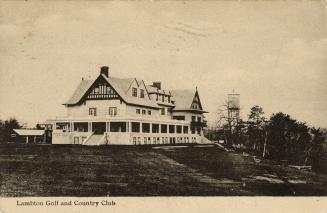 Black and white photograph of a large house with a wrap around veranda.