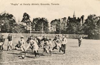 Black and white photo postcard depicting male rugby players in action. The caption at the top s ...