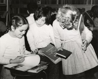 Picture of three girls looking at books.