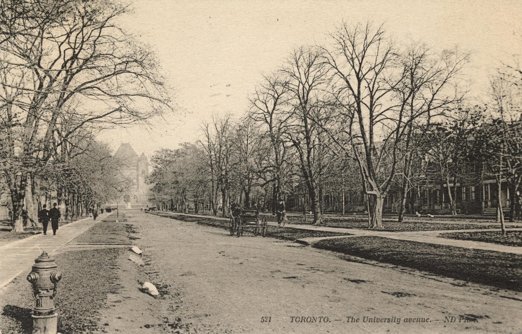 Black and white photograph of a wide, city street with trees on either side and down the median ...