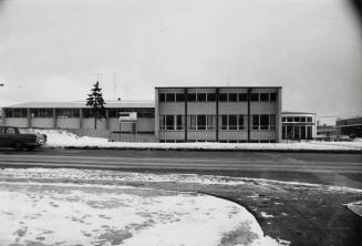 Picture of a library building and snow covered grounds and wide street. 