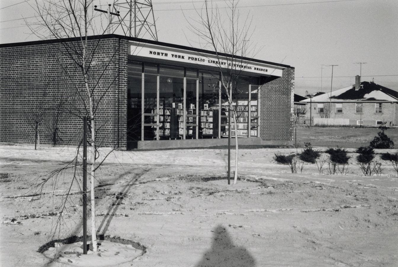 Picture of a small library building and snow covered lawn. 