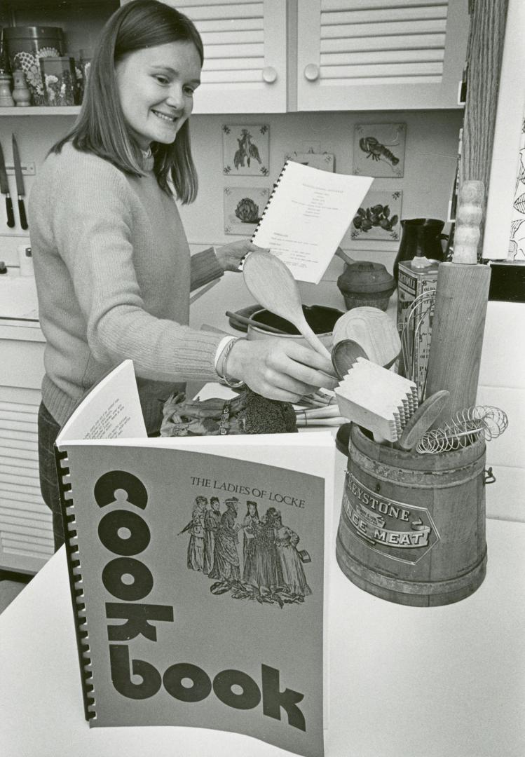 Picture of woman cooking at a stove and a cookbook displayed in front of her. 