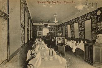 Black and white photograph of two rows of formally set tables inside a restaurant..