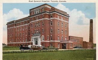 Colorized photograph of a large, square hospital building with three cars parked in front of it ...