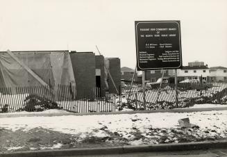 Picture of construction site with one storey being built and houses in background. 