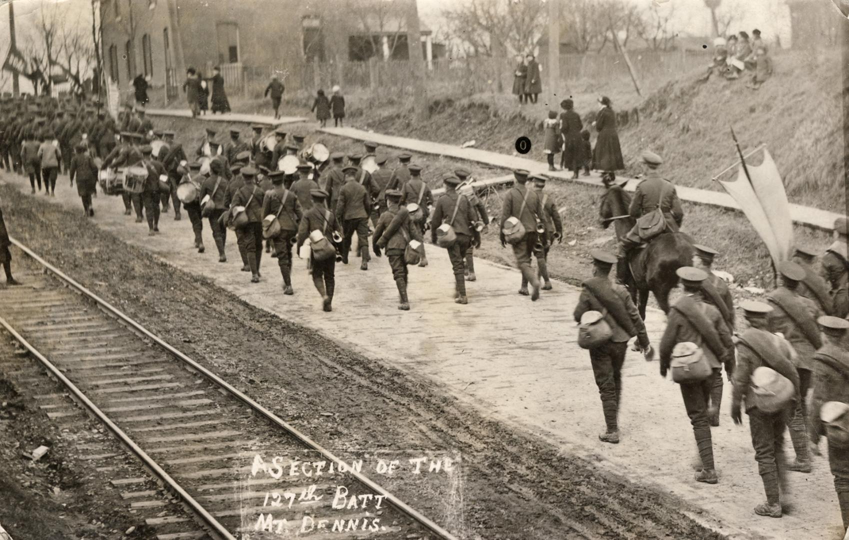 Black and white photograph of soldiers walking beside railway tracks