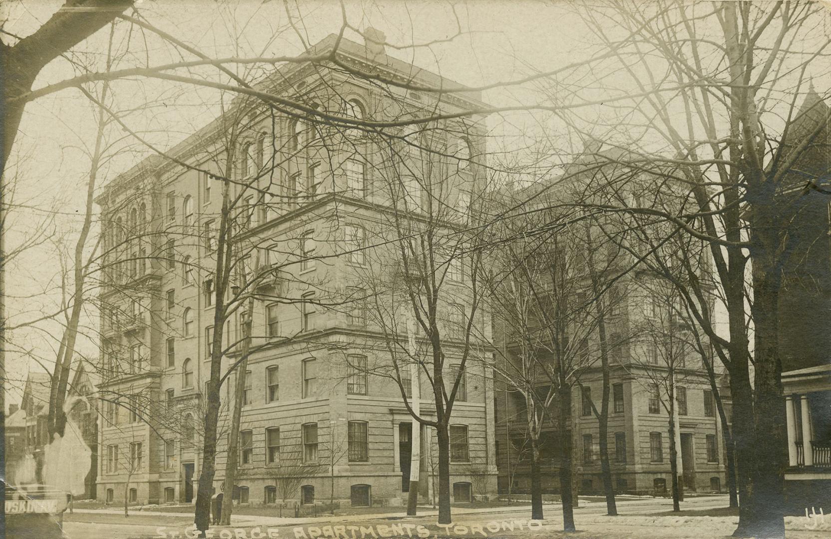 Black and white photograph of a U shaped apartment building with six floors.