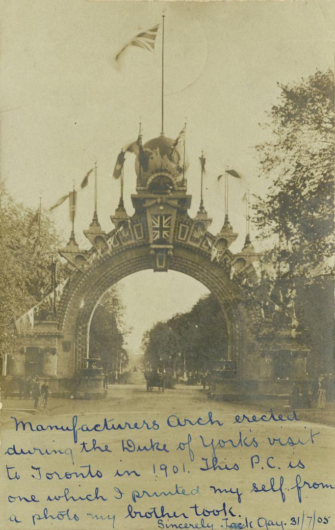 Black and white photograph of a large stone arch spanning a paved road with people and carriage ...