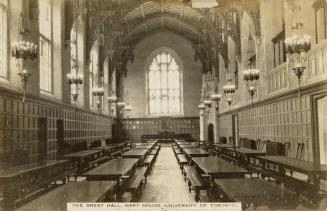 Black and white photograph of long rows of tables and benches in an elaborate dining area.