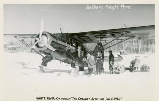 Black and white photograph of people loading a small plane in the wintertime.