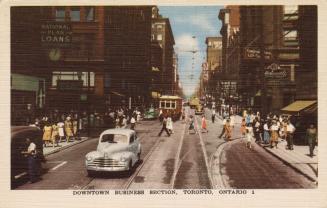 Colour postcard depicting a downtown street with a streetcar, cars, and pedestrians on the side ...