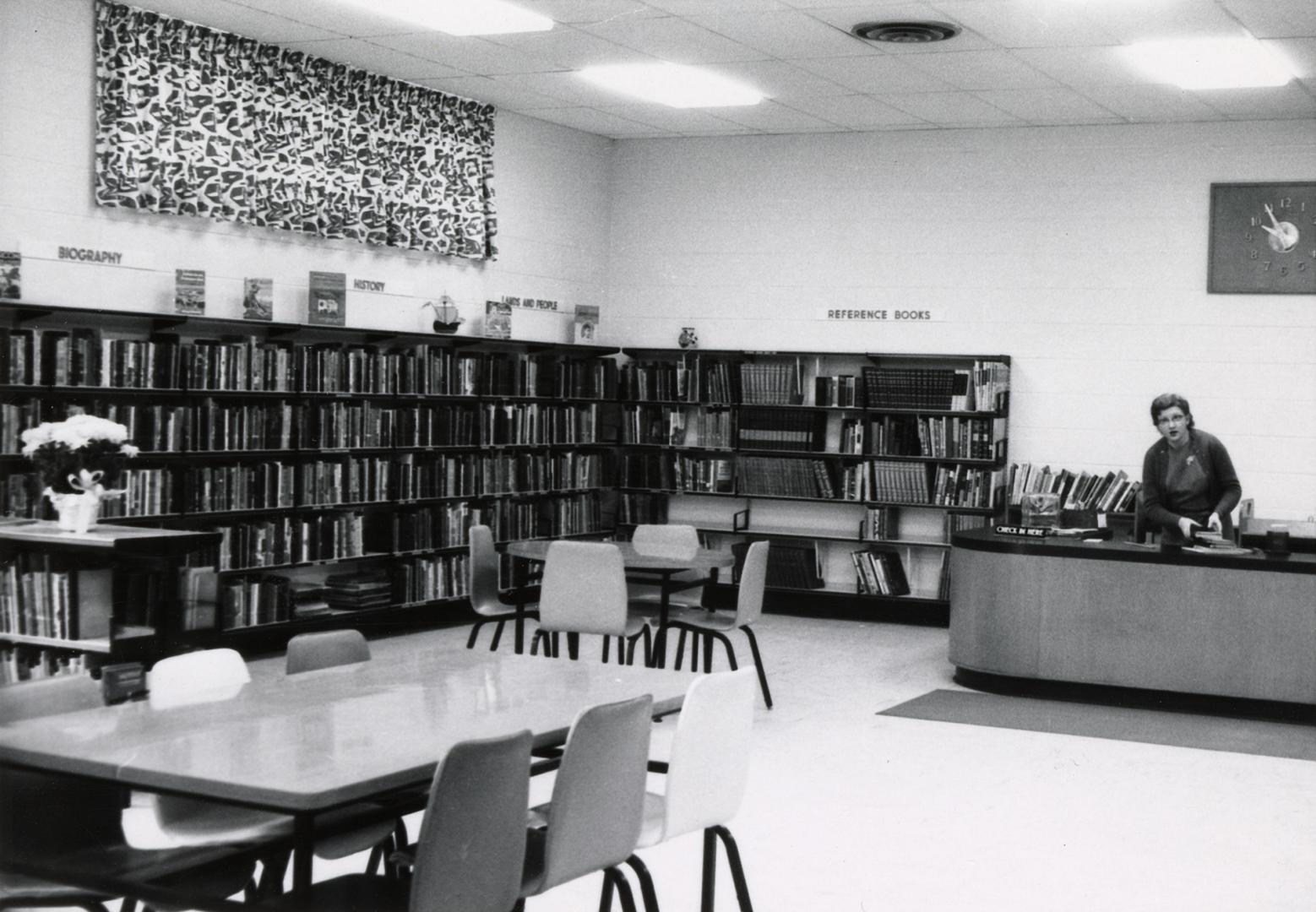 Picture of interior of library with staff at enquiry desk. 