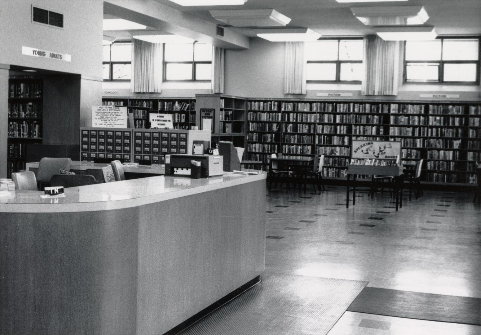 Picture of interior of library with desk and shelves of books. 