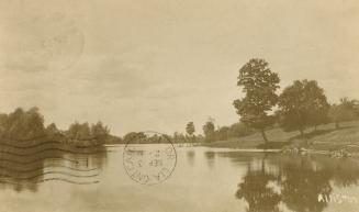 Sepia toned photograph of a narrow body of water surrounded by trees.