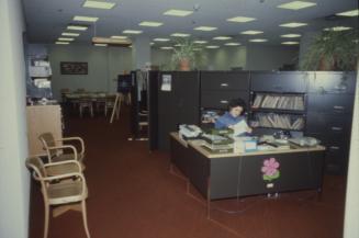 Picture of an office area with a person at a desk. 