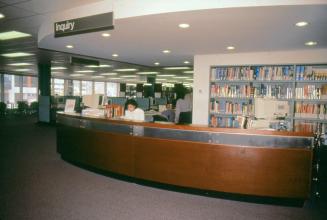 Picture of a librarian sitting at a large reference desk. 
