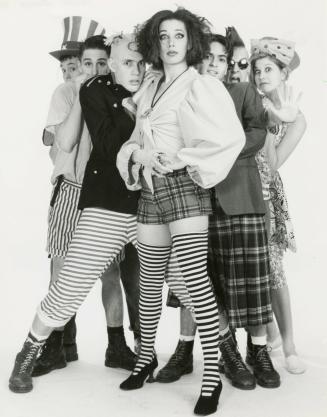 Seven young people in outrageous dress such as striped stockings, plaids and hats. Full body im…