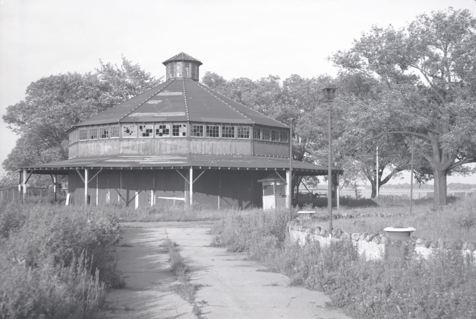 Photograph of an abandoned wooden building housing a merry-go-round. 