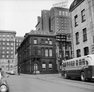Photograph of street with commercial buildings on one side and bus on right side of photo. 