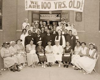 Black-and-white group photograph of approximately thirty adults arranged in several rows on the…