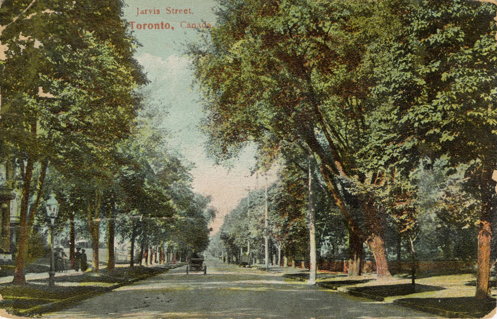 Colorized photograph of a city street bordered by large trees. People and carriages on the stre ...