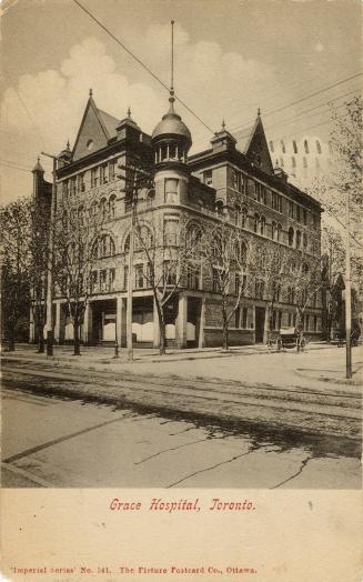 Black and while picture of a large Victorian building with a turret.